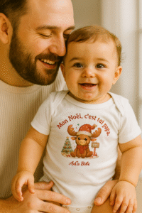 Papa tenant son bébé souriant portant un body de Noël AnCa Bébé avec le message « Mon Noël c’est toi papa », moment tendre en famille