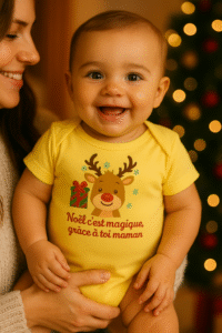 Bébé porté par sa maman, souriant, portant un body de Noël jaune avec un renne et le message Noël c’est magique grâce à toi maman — idée cadeau Noël pour jeune maman et bébé.